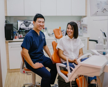 Dentist and patient smiling together in dental operating room.