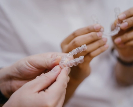 Closeup shot of two pairs of hands, each holding a clear aligner tray.