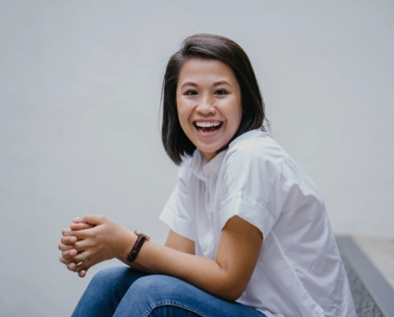 Smiling woman sits on step in office casual clothes.