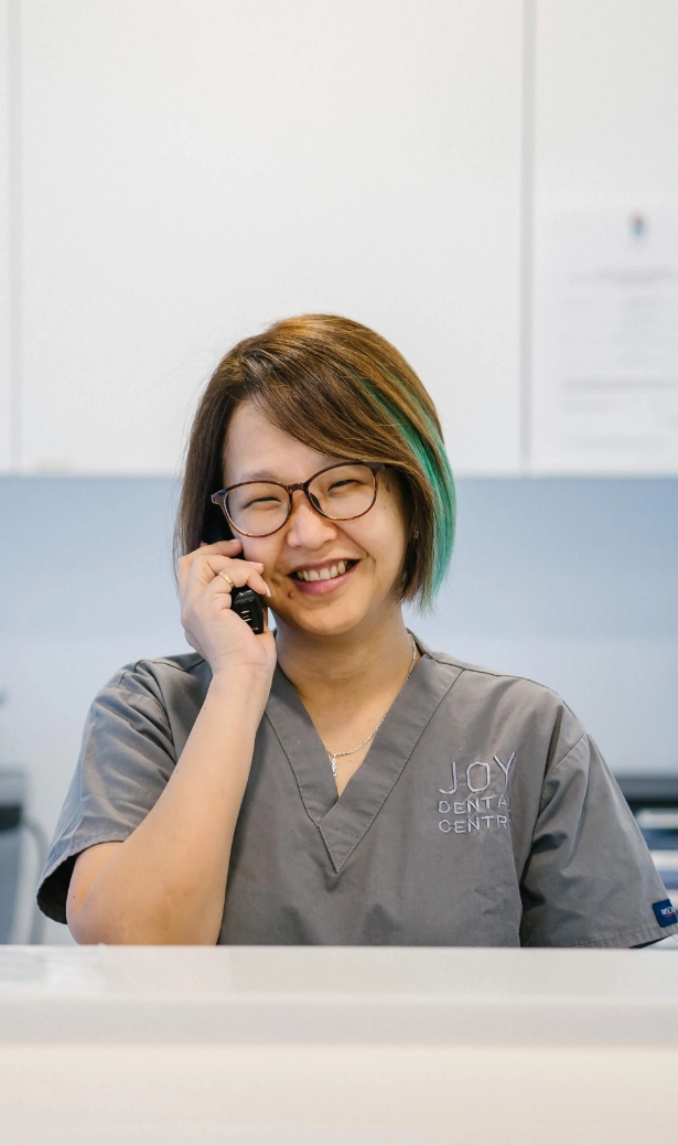 Smiling dental receptionist answers telephone in office after patient contacted them.