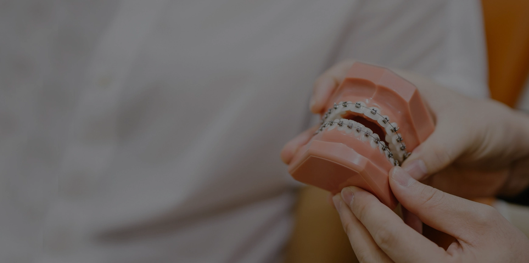 Close up shot: dentist shows model of braces to patient.