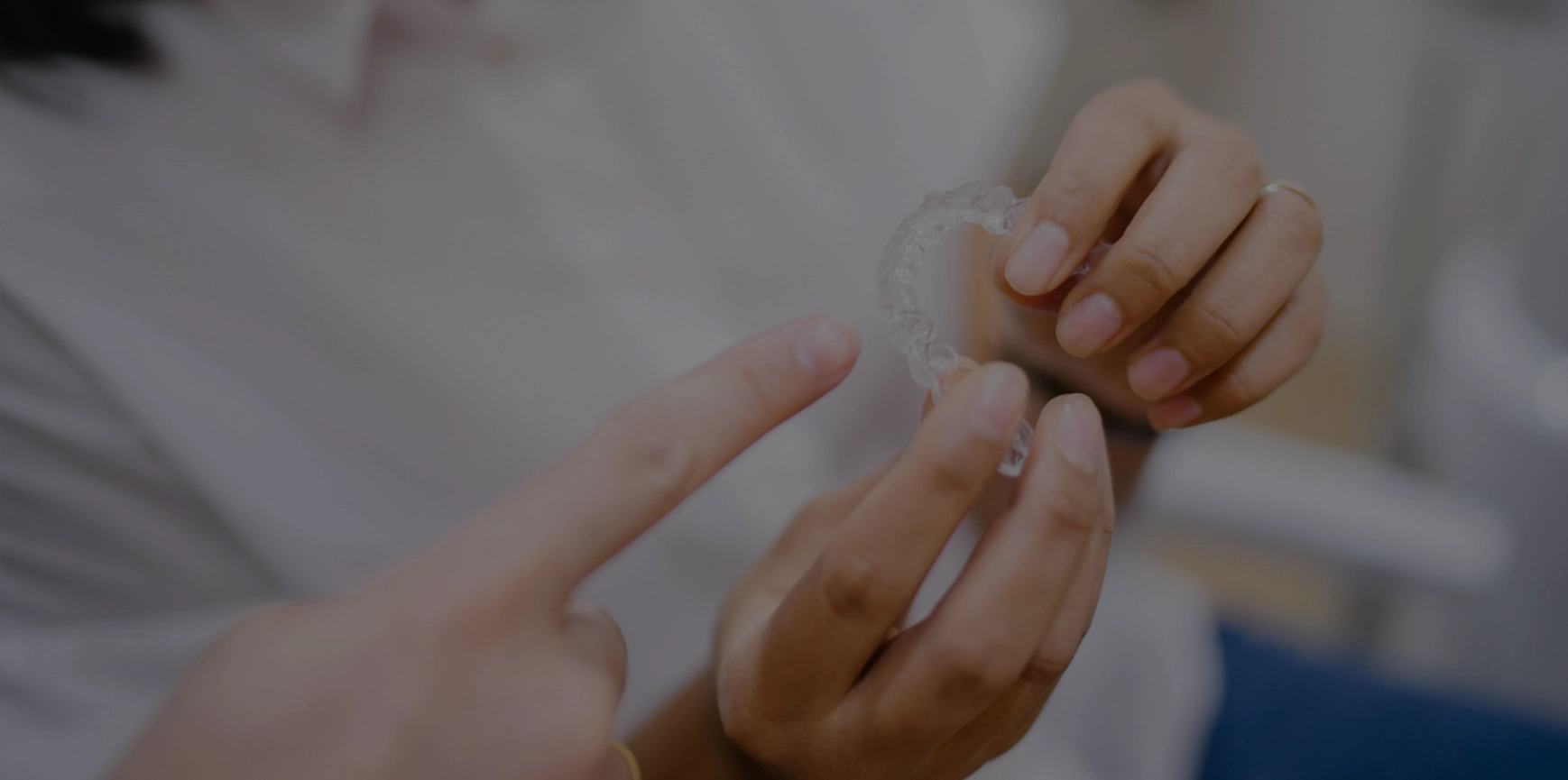 Close up shot: dentist shows model of Invisalign aligners to patient.