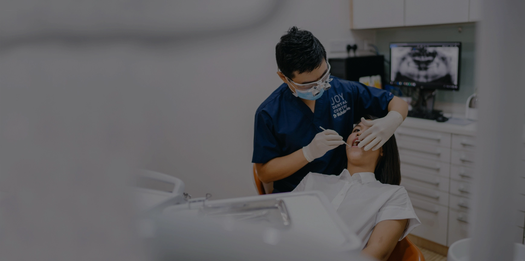 Dentist in sanitary mask performs a root canal on a patient in dental chair.