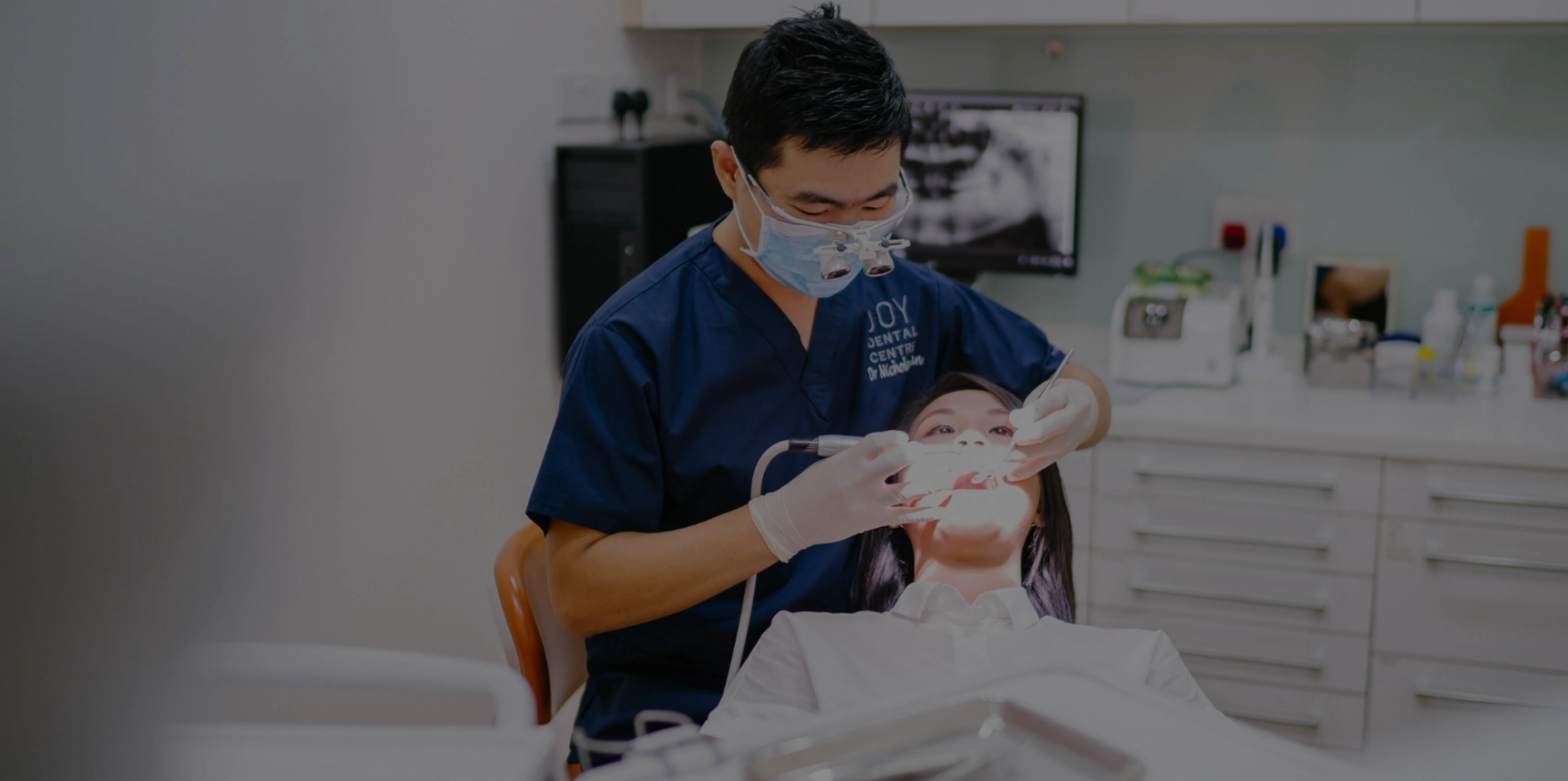 Dentist in sanitary mask operates on patient in dental chair in office.