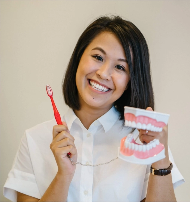 Patient holding tooth brush and mouth model.