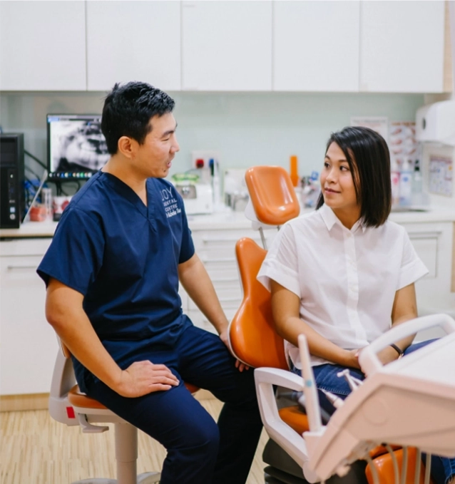 Dentist explaining information to patient sitting in dental chair.